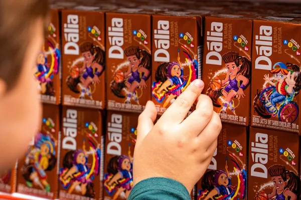 Criança escolhe caixinha do novo achocolatado Dália em prateleira. O produto foi relançado com fórmula renovada, embalagem lúdica e apoio ao Instituto do Câncer Infantil.