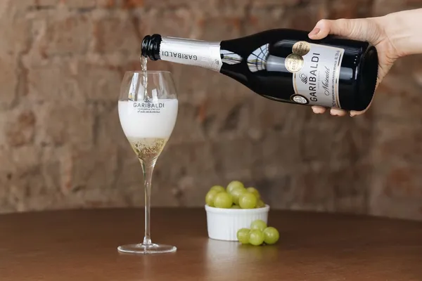 Espumante Garibaldi Moscatel sendo servido em taça personalizada da Cooperativa Vinícola Garibaldi, destaque internacional com medalha Gran Ouro no concurso francês Citadelles du Vin.