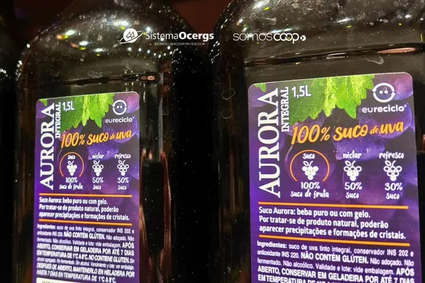 Imagem de garrafas de suco de uva integral Aurora, com rótulo destacando 100% suco de fruta, selo Eureciclo e a informação "o mais vendido do Brasil".